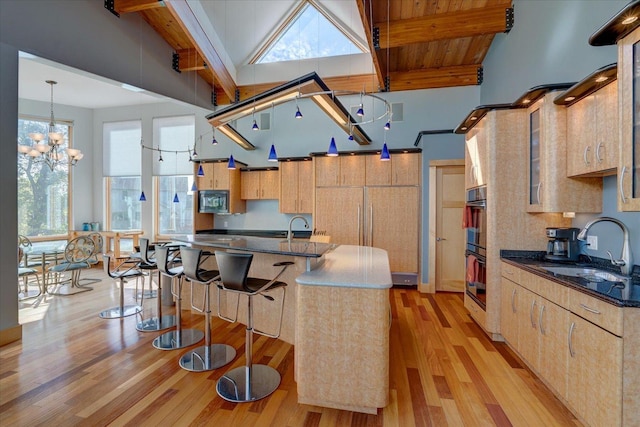 kitchen featuring dark countertops, black appliances, beam ceiling, and a sink