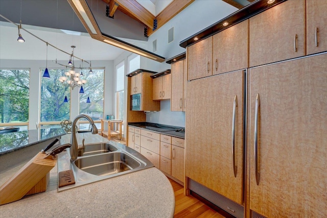 kitchen featuring dark countertops, paneled refrigerator, a sink, and decorative light fixtures