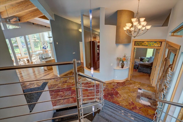 hall featuring lofted ceiling, baseboards, and an inviting chandelier