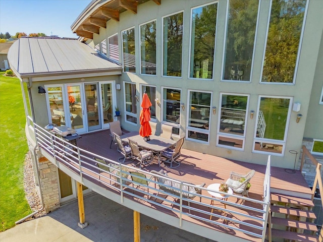 back of property featuring outdoor dining area, metal roof, a wooden deck, and a standing seam roof