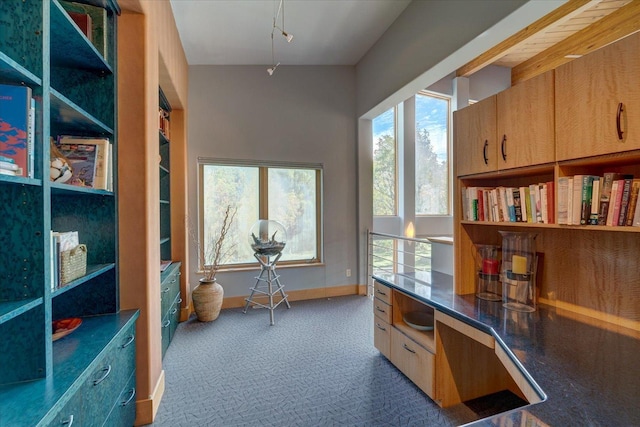 carpeted home office with built in desk and baseboards