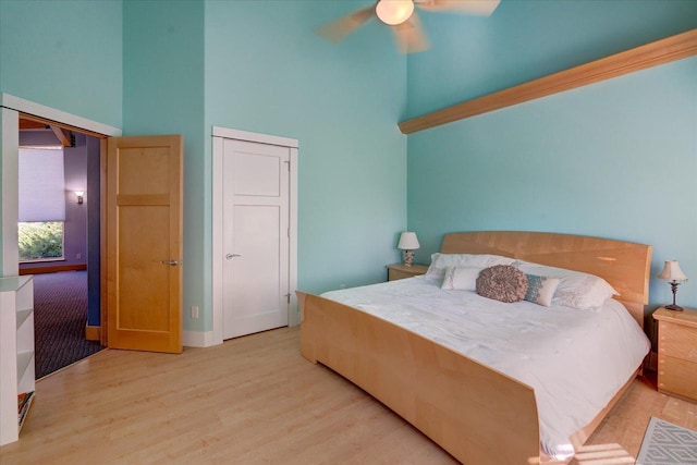 bedroom featuring a towering ceiling, light wood finished floors, and ceiling fan