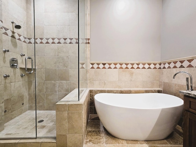 bathroom featuring a freestanding bath, a shower stall, vanity, and tile walls