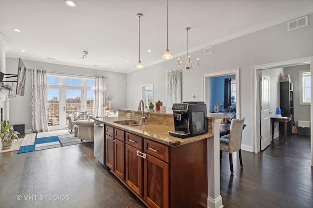 kitchen with hanging light fixtures, visible vents, open floor plan, and a sink