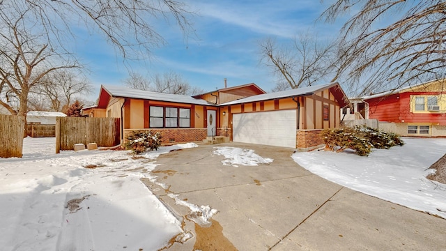 view of front facade featuring an attached garage, fence, concrete driveway, and brick siding