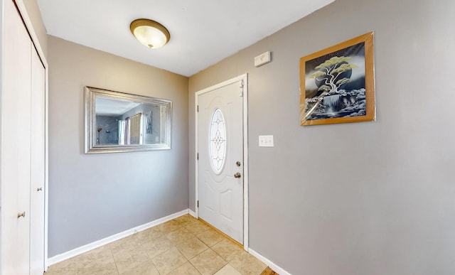 foyer entrance featuring light tile patterned flooring and baseboards