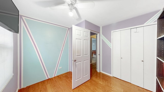 unfurnished bedroom with light wood-style floors, ceiling fan, and a closet