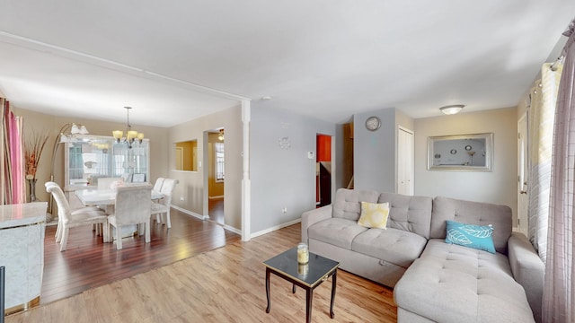 living area featuring baseboards, a chandelier, and wood finished floors