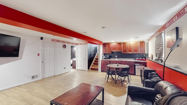 living area with baseboards, visible vents, light wood finished floors, and stairs