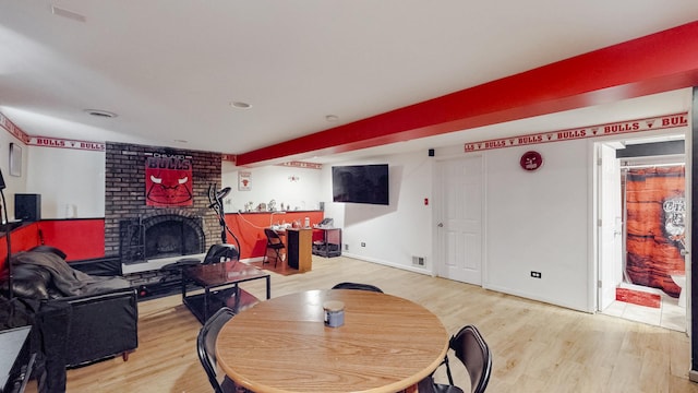 dining space featuring light wood finished floors, baseboards, a fireplace, and visible vents