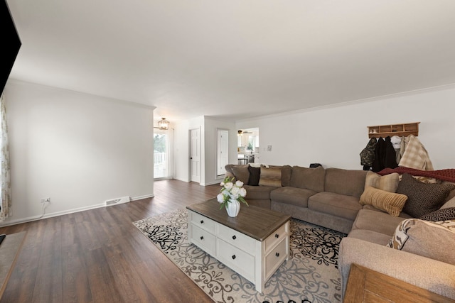 living room featuring visible vents, crown molding, baseboards, dark wood-style floors, and a notable chandelier