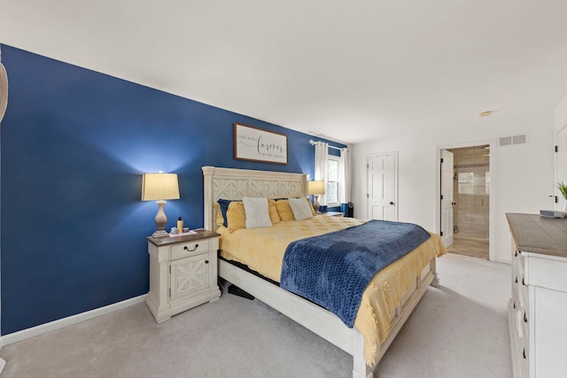 bedroom featuring baseboards, light colored carpet, visible vents, and ensuite bath
