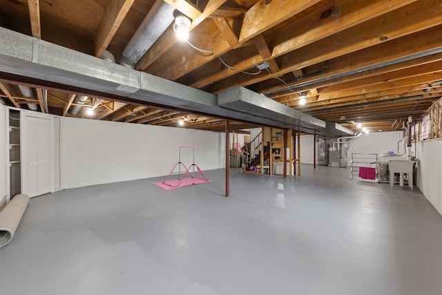 unfinished basement with a sink and water heater