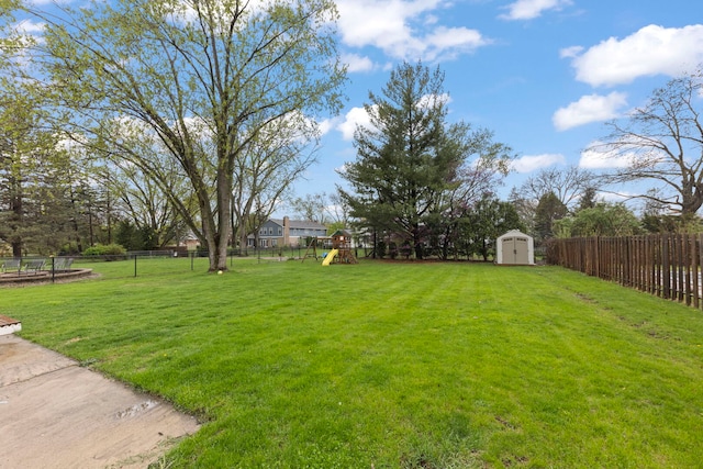 view of yard with a playground, an outbuilding, a fenced backyard, and a shed