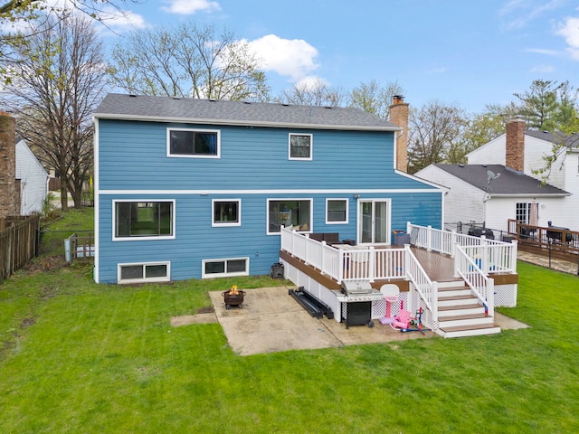 rear view of house featuring a wooden deck, a chimney, a patio, a yard, and a fire pit