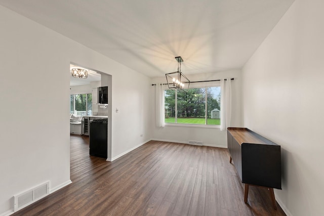 unfurnished dining area featuring baseboards, an inviting chandelier, dark wood-style floors, and visible vents