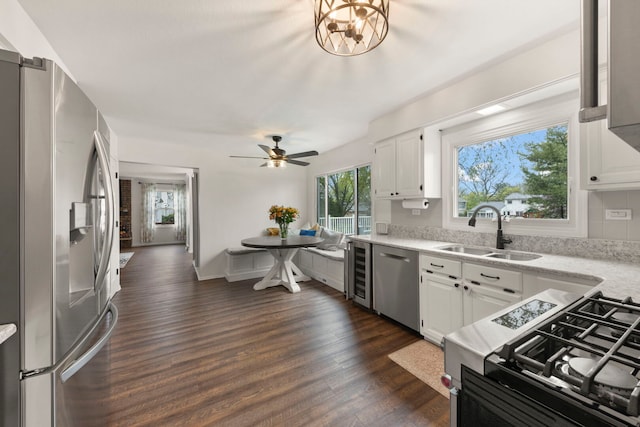 kitchen with dark wood-style flooring, wine cooler, white cabinets, a sink, and appliances with stainless steel finishes