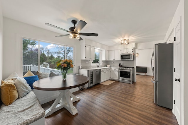 kitchen featuring dark wood-style flooring, appliances with stainless steel finishes, a sink, light countertops, and white cabinets