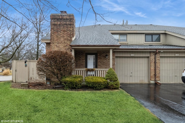 view of front facade featuring driveway, a chimney, roof with shingles, a front lawn, and brick siding