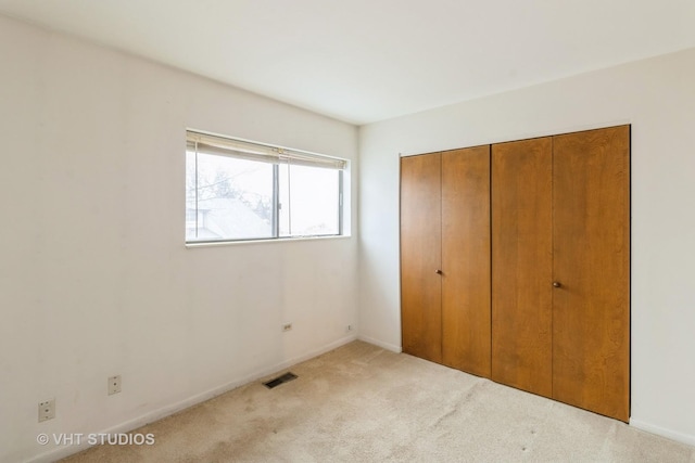 unfurnished bedroom with baseboards, a closet, visible vents, and carpet flooring