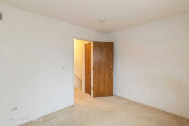 spare room with carpet flooring, visible vents, and baseboards