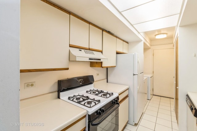 kitchen featuring light tile patterned floors, gas range, light countertops, cream cabinetry, and under cabinet range hood