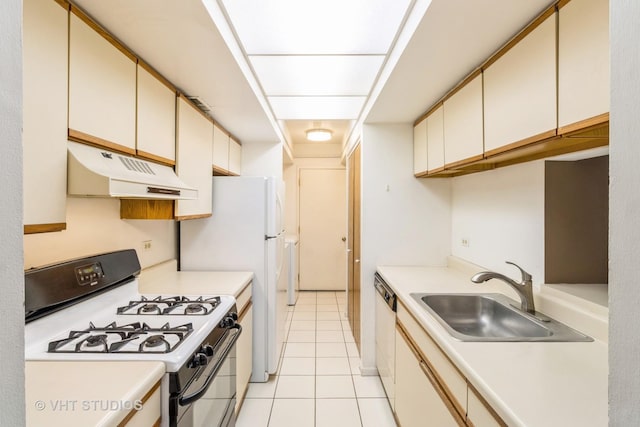 kitchen featuring under cabinet range hood, a sink, range with gas stovetop, light countertops, and cream cabinetry