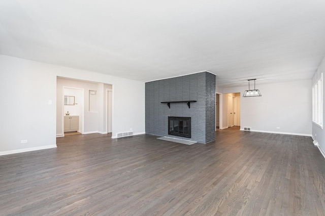 unfurnished living room featuring baseboards, a fireplace, visible vents, and dark wood-type flooring