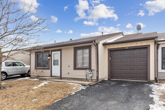 ranch-style house with an attached garage and aphalt driveway