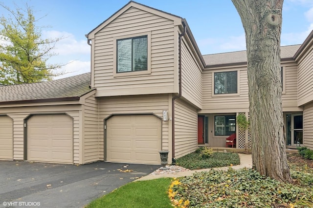 view of front facade with aphalt driveway, a shingled roof, and a garage