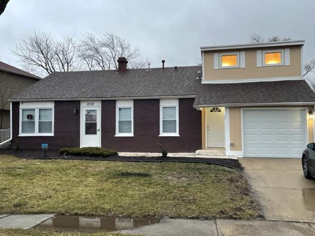 view of front of home with a shingled roof, a front lawn, and concrete driveway