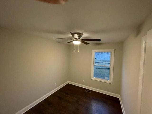 spare room with a ceiling fan, visible vents, baseboards, and dark wood-type flooring