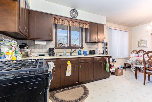 kitchen featuring light countertops, decorative backsplash, dark brown cabinetry, a sink, and gas range