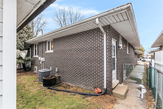 view of side of home with brick siding and fence