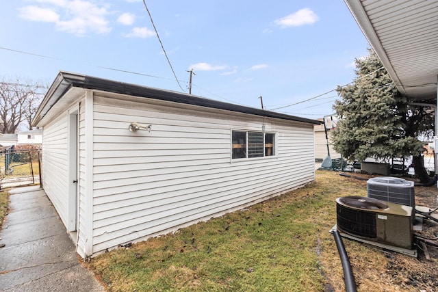 view of home's exterior with fence, a lawn, and central AC