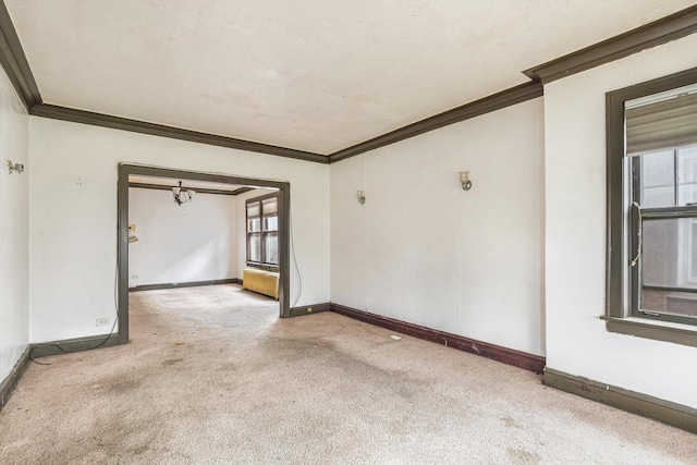 carpeted spare room featuring baseboards and crown molding