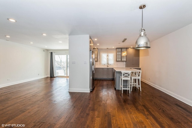 kitchen featuring a center island, light countertops, hanging light fixtures, freestanding refrigerator, and a kitchen breakfast bar