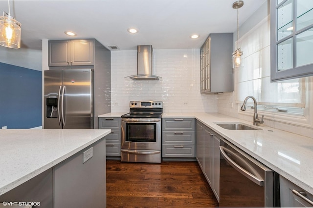 kitchen featuring wall chimney range hood, stainless steel appliances, a sink, and decorative light fixtures