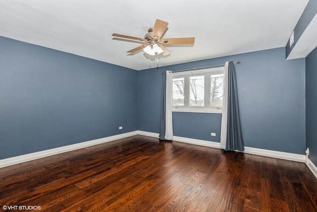 empty room with dark wood-type flooring, a ceiling fan, and baseboards