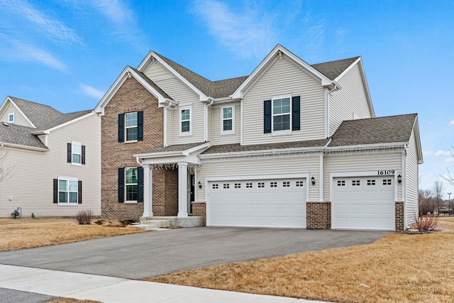 view of front of home with driveway, roof with shingles, and brick siding