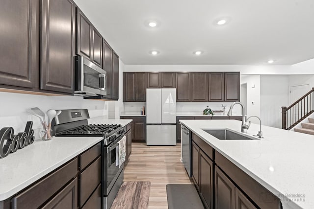 kitchen with stainless steel appliances, recessed lighting, light wood-style floors, a sink, and dark brown cabinets