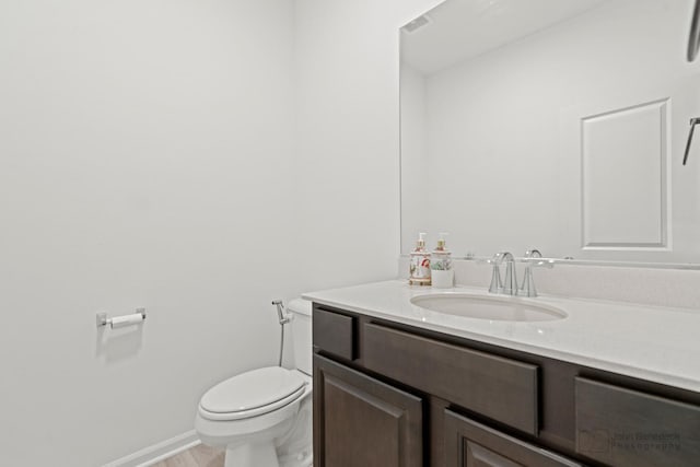 bathroom featuring baseboards, vanity, and toilet