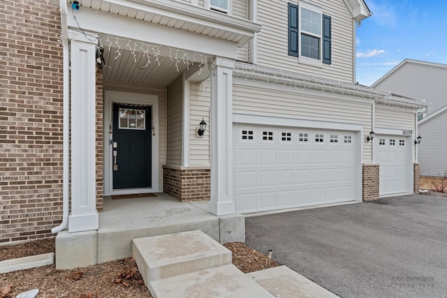 doorway to property featuring brick siding and aphalt driveway