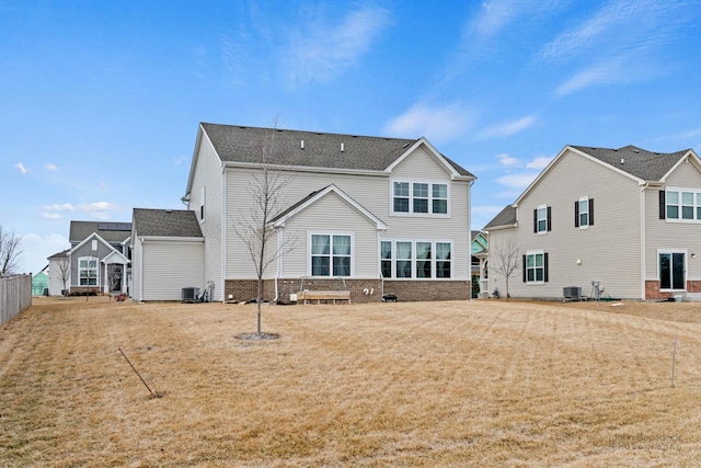 rear view of property with a yard, a shingled roof, cooling unit, and brick siding