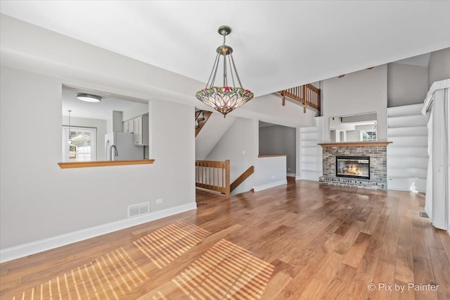 unfurnished living room featuring visible vents, a fireplace, baseboards, and wood finished floors