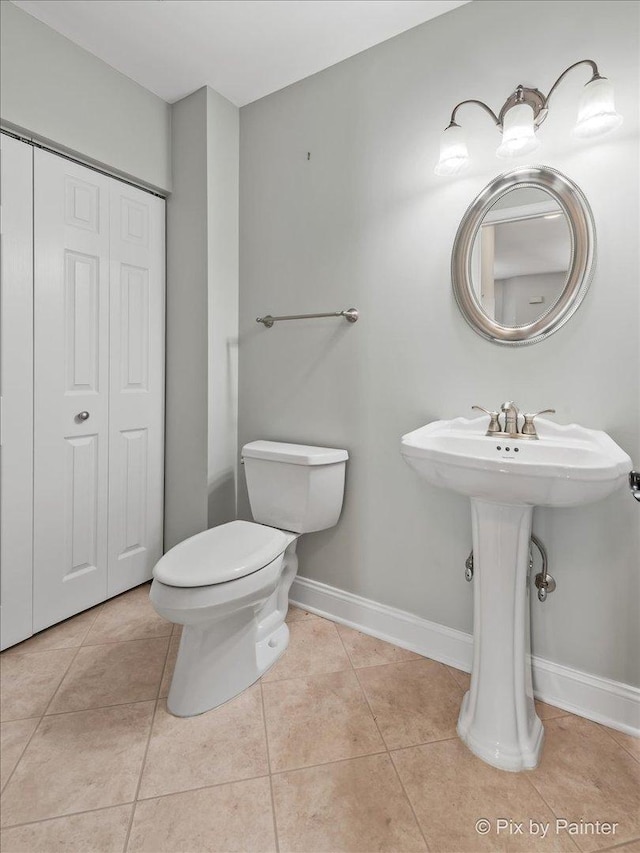 bathroom with baseboards, toilet, and tile patterned floors