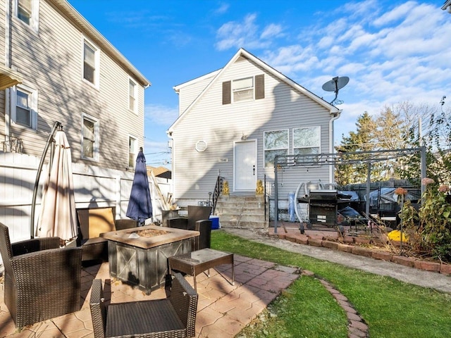 rear view of property with entry steps, an outdoor living space with a fire pit, a patio, and fence