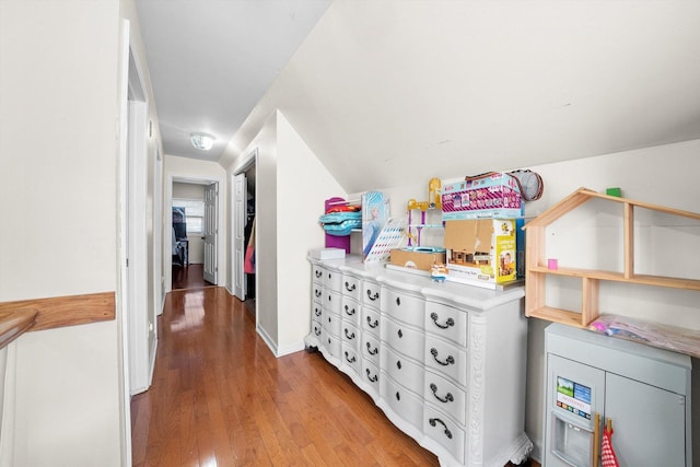 corridor featuring lofted ceiling, light wood-type flooring, and baseboards