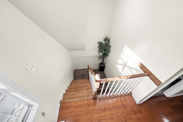 staircase with vaulted ceiling and hardwood / wood-style floors