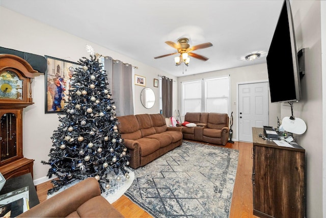 living room featuring ceiling fan, baseboards, and wood finished floors